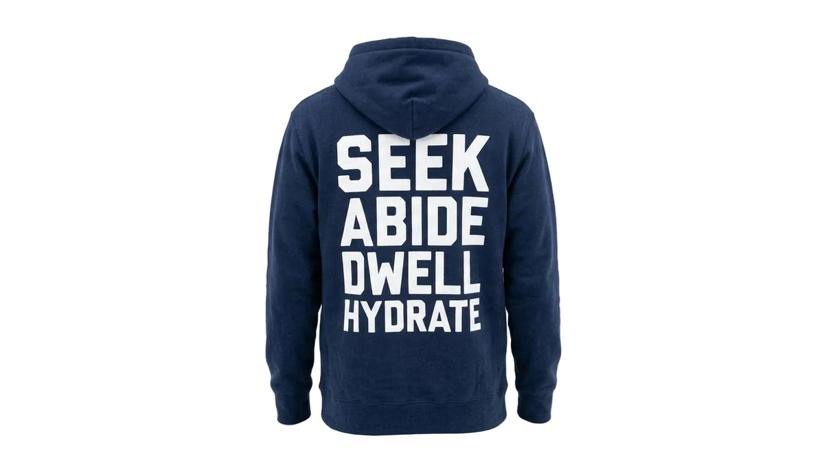 A navy blue hoodie shown from the back, featuring the words 'SEEK ABIDE DWELL HYDRATE' printed in large white capital letters.