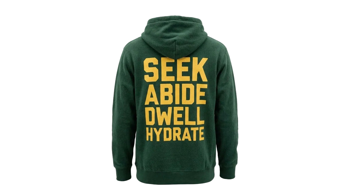 A dark green hoodie shown from the back, featuring the words 'SEEK ABIDE DWELL HYDRATE' printed in large yellow capital letters.