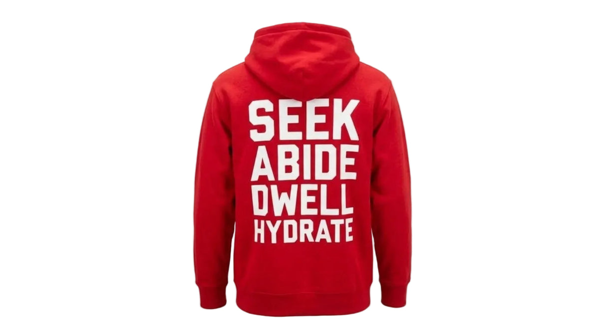 A red pullover hoodie shown from the back, featuring the words 'SEEK ABIDE DWELL HYDRATE' printed in large white capital letters on the back, set against a plain white background.