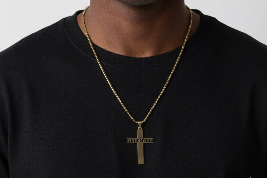 Man wearing a black shirt and gold necklace with a cross pendant on a plain background