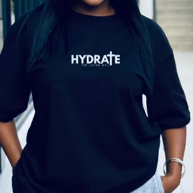 Woman wearing a black t-shirt with 'HYDRATE' logo outdoors.