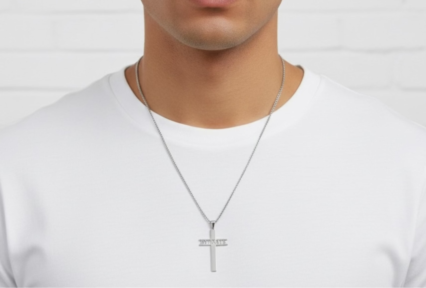 Man wearing a silver cross necklace that reads HYDRATE horizontally on a plain background