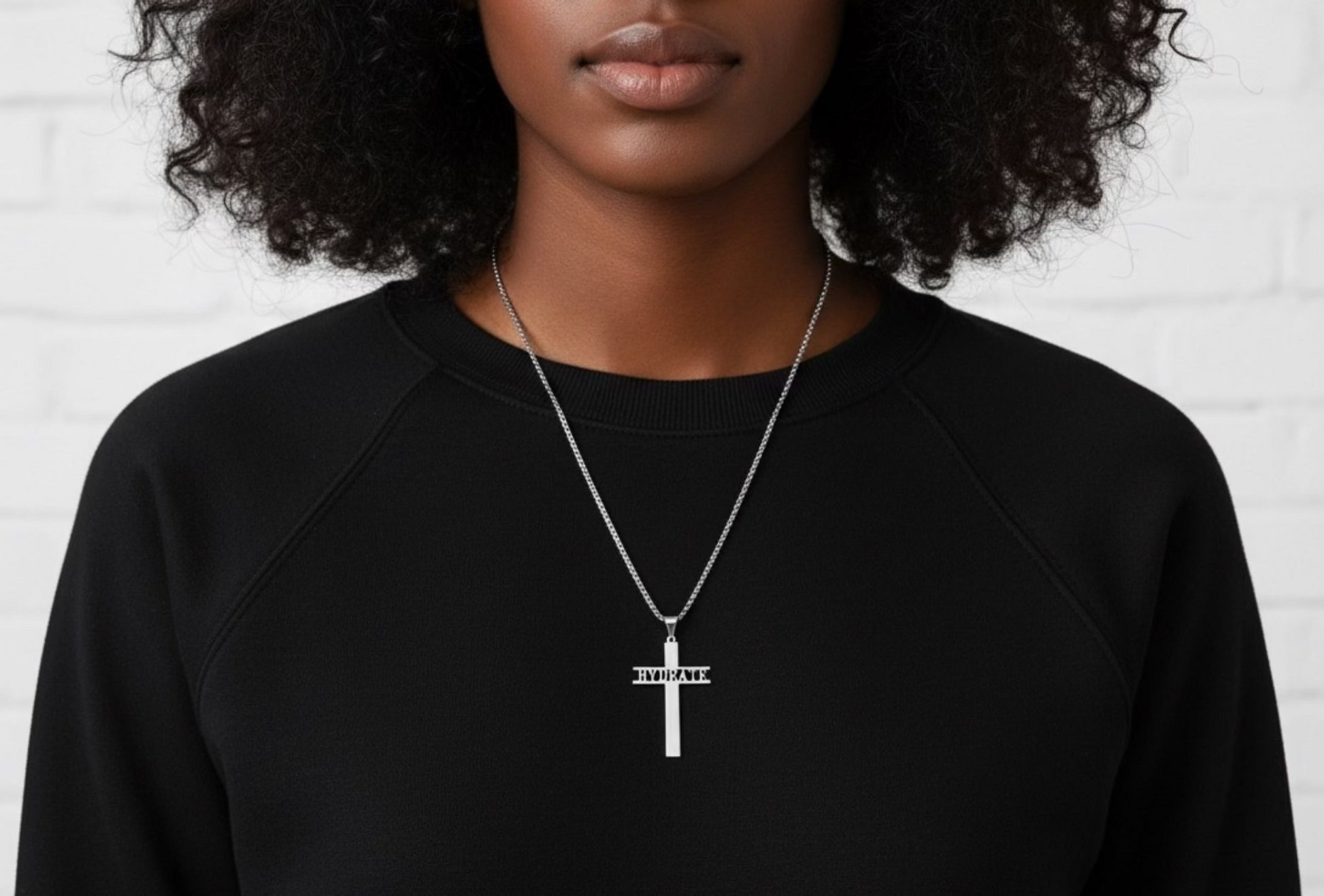 Person wearing a black sweatshirt with a necklace featuring a cross pendant.